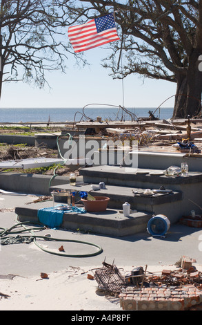 American flag waves over foundation of beach house with few remaining posessions still stacked on porch steps six months after Hurricane Katrina destroyed the Mississippi gulf coast Stock Photo