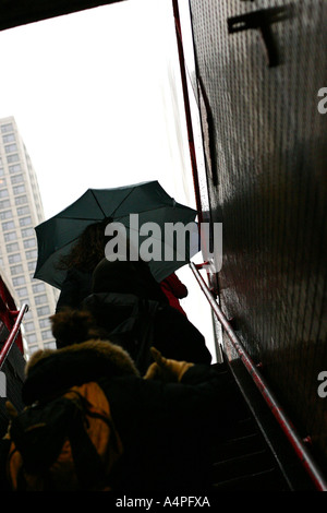People opening umbrellas as the climb the stairs from the underground train in Chicago, IL USA Stock Photo