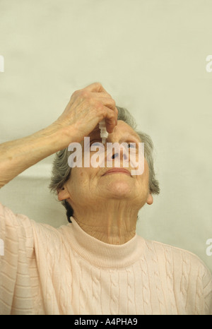 elderly woman applying eye drops Stock Photo