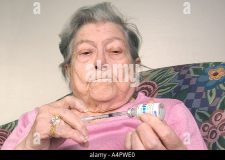 Diabetic Senior caucasion woman in pink blouse prepares syringe with insulin diabetes Stock Photo