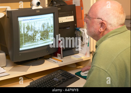 elderly man working on an old photograph on his home computer Stock Photo