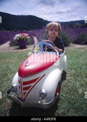 child sitting in old metal play car pretenting to drive Stock Photo