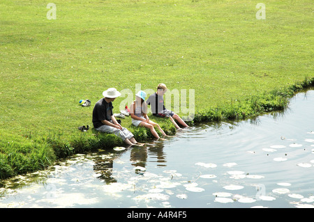 Man and children with feet in the water Stock Photo