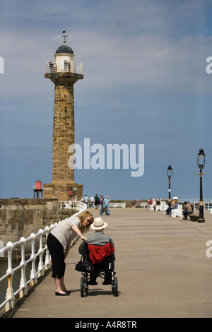 Woman talking to a man in a wheelchair on Whitby pier North Yorkshire England UK Stock Photo