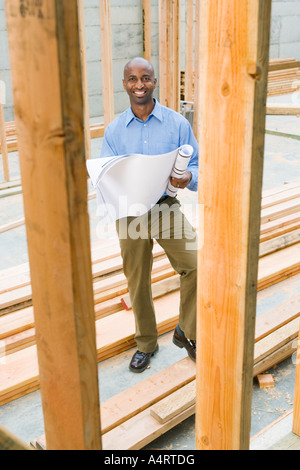 Portrait of young male professional at building site with plans Stock Photo