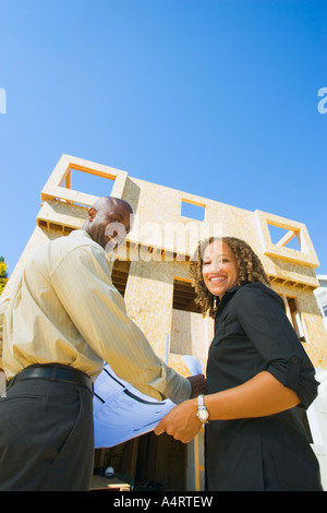 Portrait of smiling young couple with new home under construction. togetherness two people wife woman women wood wooden young Stock Photo