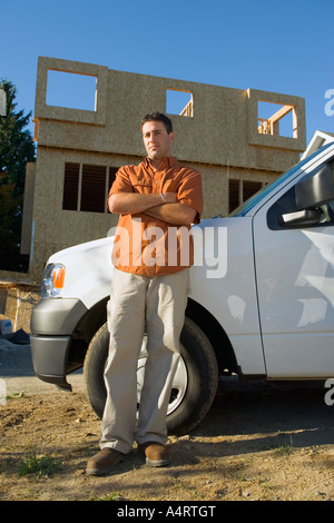 Portrait of young male contractor with truck at building site.  vertical wall white wood wooden work worker workers working Stock Photo