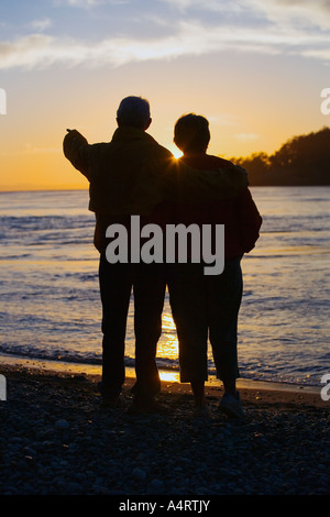 Silhouette of couple watching sunset on beach Stock Photo