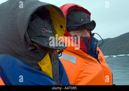 Passengers on an open boat well wrapped up against the cold and wet, Angmagssalik Fjord, East Greenland Stock Photo