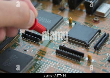 hand holding multimeter probe and testing printed circuit board component Stock Photo