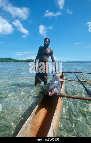 Robert a shark caller from Kontu village on the West Coast of New Ireland brings in a dolphin he speared Stock Photo