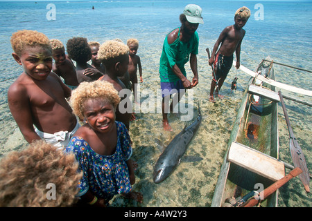 Obet a shark caller from Kontu village is surrounded by excited children after bringing in a shark he caught Stock Photo