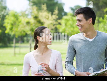 Young couple smiling at each other in park Stock Photo