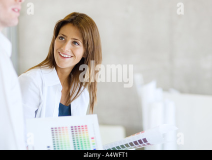 Interior decorator with color swatches smiling at colleague Stock Photo