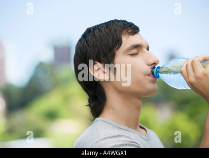 Young man drinking water from bottle Stock Photo