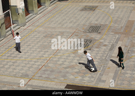 Young students playing soccer in courtyard Stock Photo