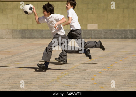 Young students playing basketball with a soccer ball in courtyard Stock Photo