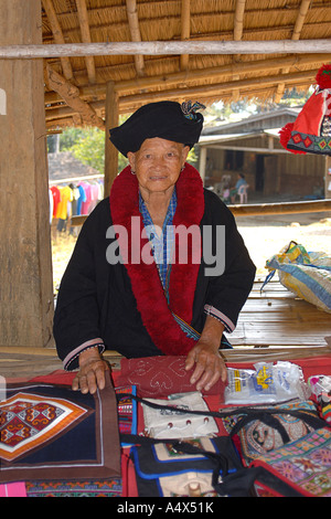 Yao woman in distinctive tribal costume vending handicrafts from a market stall Near Chiang Rai Thailand Stock Photo