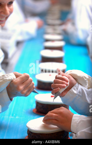 PRODUCTION LINE WORKERS ADDING THE FINISHING TOUCHES TO CHRISTMAS CAKES DESTINED FOR UK SUPERMARKETS Stock Photo