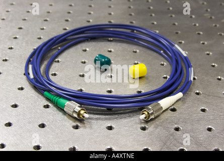 A Kevlar-jacketed optical cable coiled on an optical table, shallow depth of focus Stock Photo