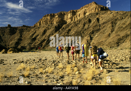 A group of nine hikers walking along the rocky bed of the Fish River Canyon in southern Namibia south west Africa Stock Photo