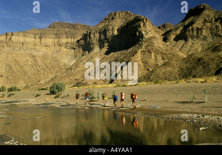 A group of five hikers walking along the rocky bed of the Fish River Canyon in southern Namibia south west Africa Stock Photo