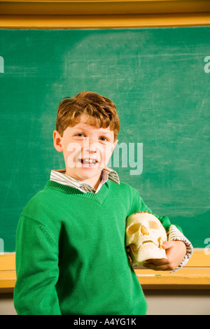 Boy holding skull in classroom Stock Photo