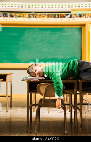 Boy sleeping on desks in classroom Stock Photo