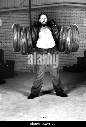 Man carrying 8 tyres Stock Photo