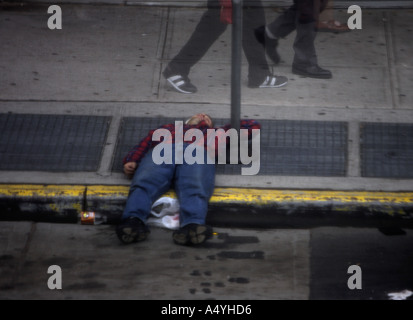 People walking by man laying dawn on street Brooklyn New York USA Stock Photo