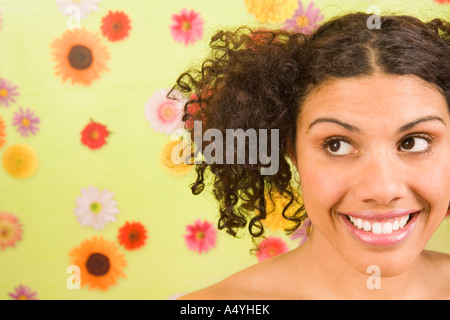 Woman looking sideways in front of flower background Stock Photo