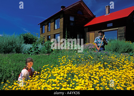 Middle aged couple with long hair working in their organic flower garden in New Brunswick Eastern Canada North America Stock Photo