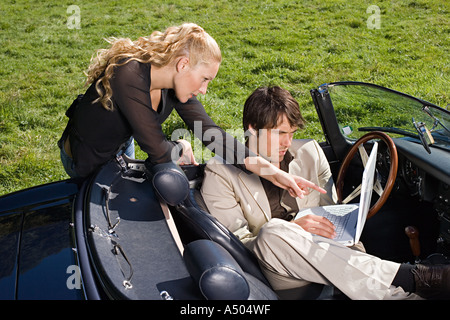 Couple in convertible with laptop Stock Photo