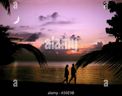 couple walking along a tropical beach at sunset Maldives Indian Ocean Stock Photo