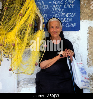 PORTRAIT OF AN OLD GREEK WOMAN SITTING BESIDE FISHING NETS Stock Photo