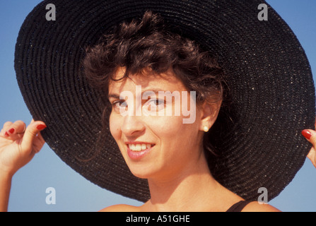 Woman holding large brim black hat closeup face eyes portrait smiling happy laughs Stock Photo