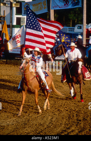 Cowgirl Carrying American Flag Riding Palomino Horse and Cowboy Carrying Indiana Flag Riding Quarter Horse Into Rodeo Arena Stock Photo