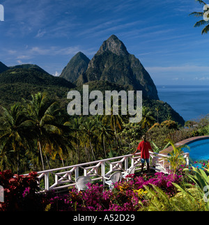 View over valley of palm trees with man on veranda dominated by Petit and Gros Piton beyond St Lucia The Caribbean Stock Photo