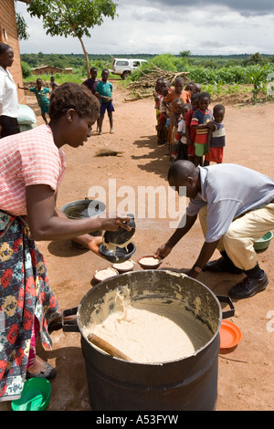 Serving phala to hungry children as part of the Joseph Project feeding programme in the village of Buli, Malawi, Africa Stock Photo