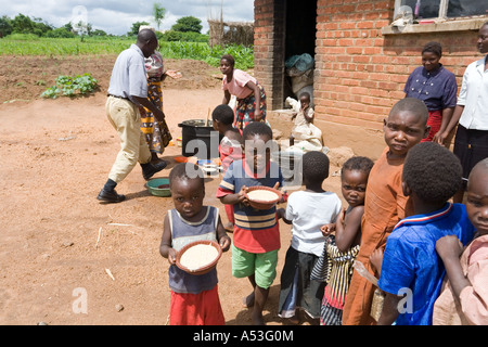 Serving phala to hungry children as part of the Joseph Project feeding programme in the village of Buli, Malawi, Africa Stock Photo