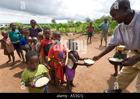 Serving phala to hungry children as part of the Joseph Project feeding programme in the village of Buli, Malawi, Africa Stock Photo