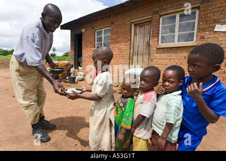 Serving phala (maize porridge) to hungry children as part of the Joseph Project feeding programme in the village of Buli, Malawi, Africa Stock Photo