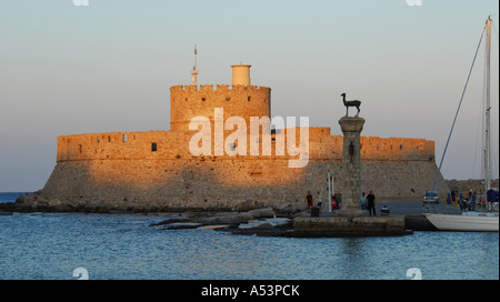 The fortress of St Nicholas, which guards the entrance to Mandraki harbour in Rhodes Town Greece with a deer statue in front Stock Photo