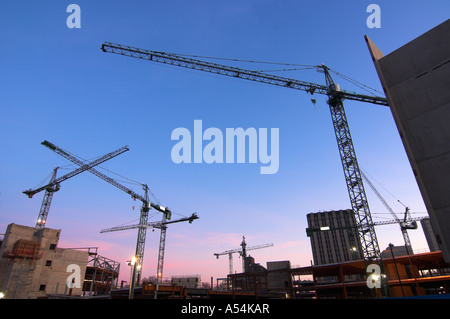 Multiple construction cranes against blue sky at building site Stock Photo