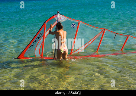 Woman tourist in bikini on her own standing in sea holding windsurfing sail Stock Photo