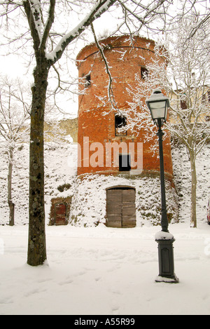 A round red brick tower stand stark against the snow covered streets Citerna Umbria Italy Stock Photo