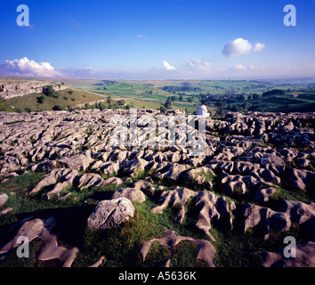 Woman admiring the view from the top of Malham Cove in the late afternoon sun. Yorkshire Dales England UK. Stock Photo