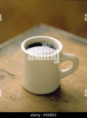 Mug of coffee sitting on corner of table Stock Photo