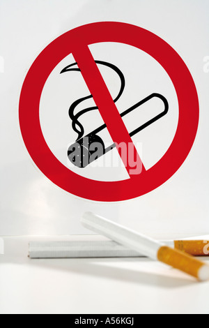 Two cigarettes in front of no smoking sign board Stock Photo