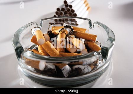 Full ashtray in front of cigarettes pile Stock Photo